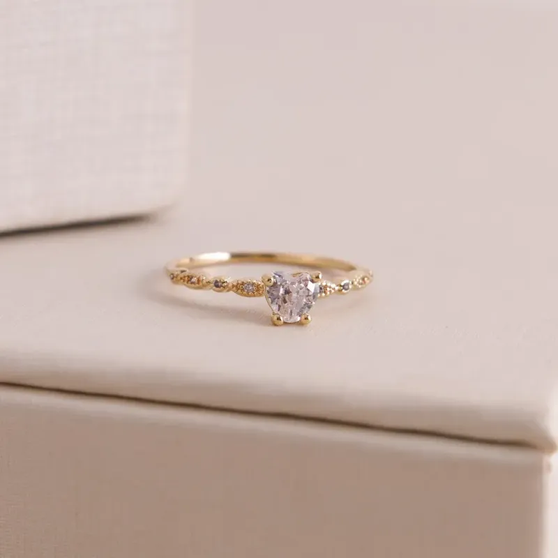 ANEL SOLITARIO COM CORAÇÃO DE CRISTAL E TRANÇADO COM ZIRCONIAS BANHADO A OURO 18K