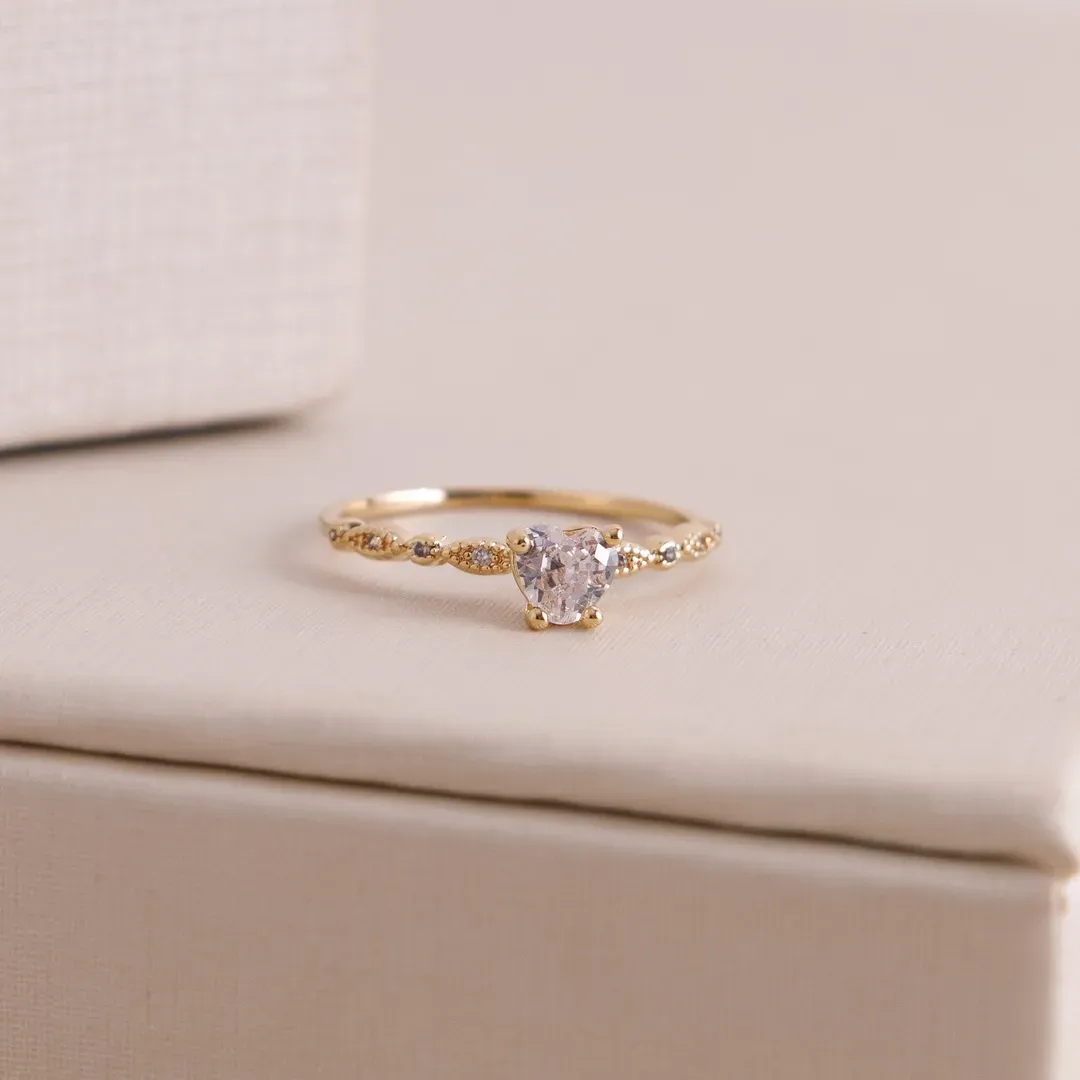 ANEL SOLITARIO COM CORAÇÃO DE CRISTAL E TRANÇADO COM ZIRCONIAS BANHADO A OURO 18K