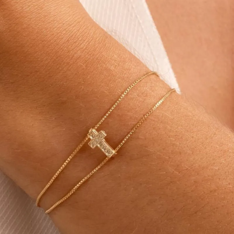 Pulseira com crucifixo cravejada com zircônias banhada a ouro 18k ajustável.